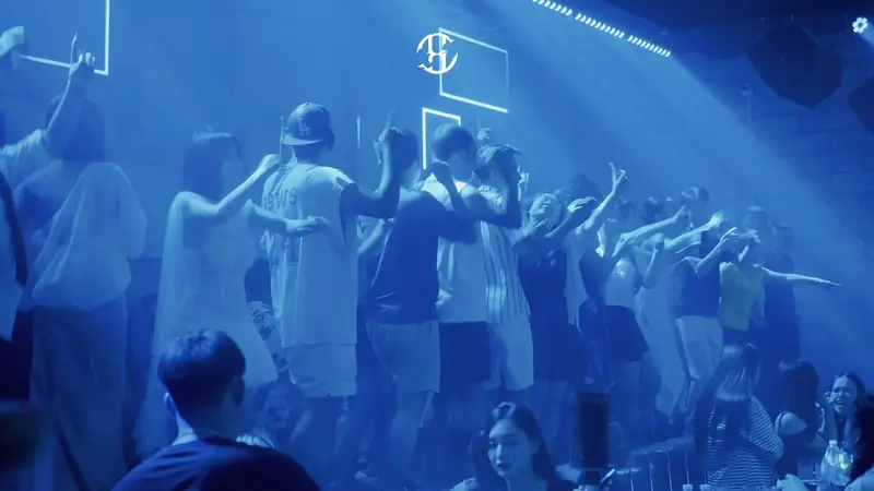Sàn nhảy COCA Club Hạ Long kín khách dưới ánh đèn xanh, tường gạch treo khung neon và monogram COCA